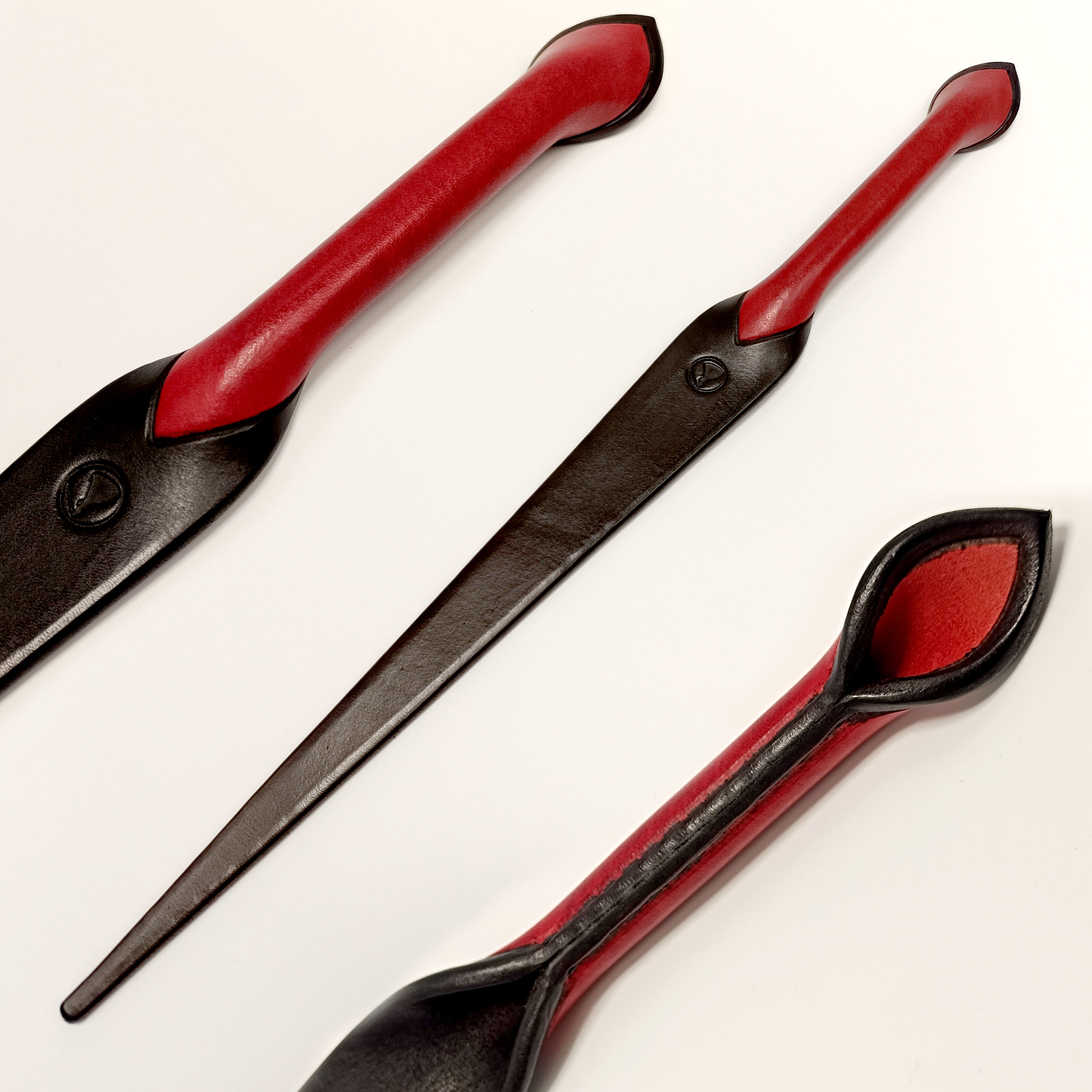 Spankingová plácačka z tlusté kůže ve tvaru nože s černou špičkou a červenou rukojetí. Cena 3000 Kč 